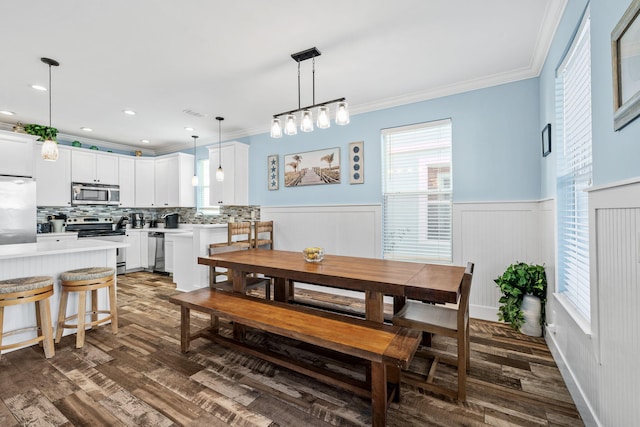 dining area with a wainscoted wall, ornamental molding, dark wood-style flooring, and recessed lighting