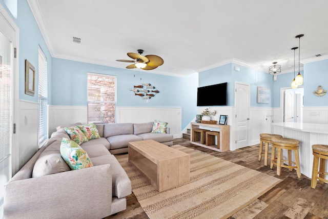 living room with ceiling fan, ornamental molding, wood finished floors, and wainscoting