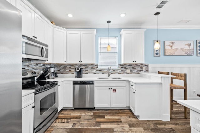 kitchen with stainless steel appliances, visible vents, ornamental molding, a sink, and a peninsula