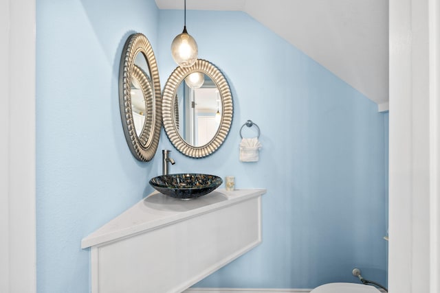 half bathroom featuring toilet, vaulted ceiling, and vanity