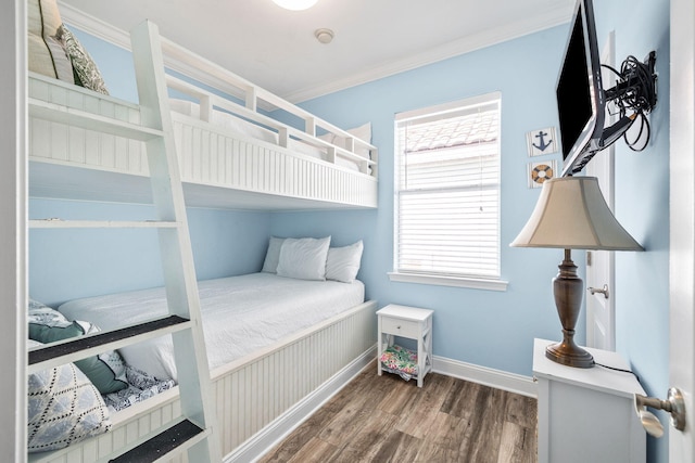 bedroom with ornamental molding, wood finished floors, and baseboards