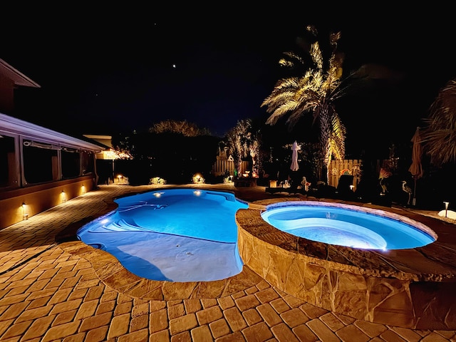 pool at twilight featuring an in ground hot tub and a patio