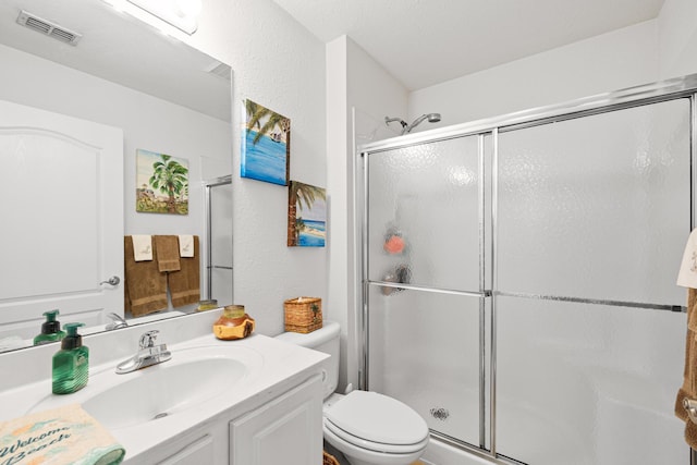 bathroom with toilet, a shower with door, and vanity