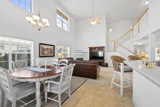 dining room featuring light tile patterned floors, a towering ceiling, and ceiling fan with notable chandelier