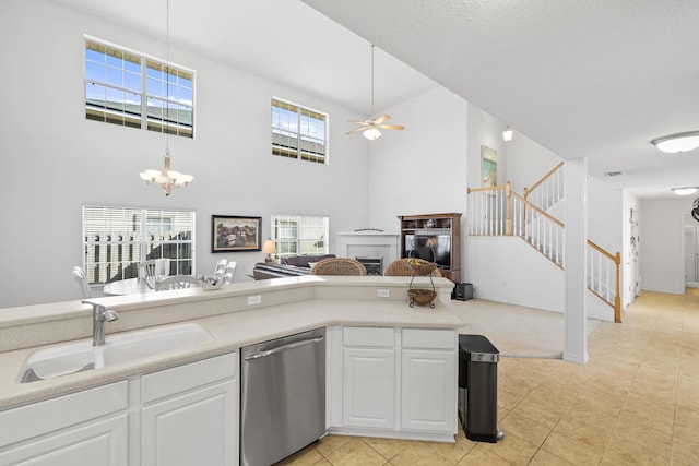 kitchen with stainless steel dishwasher, white cabinets, sink, and ceiling fan with notable chandelier