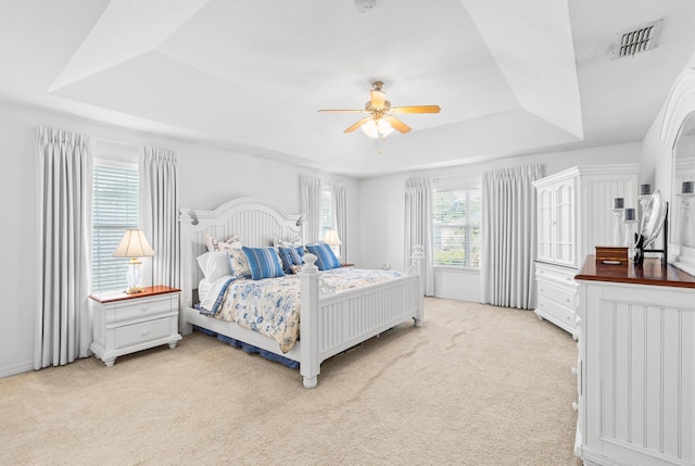 bedroom featuring ceiling fan, light carpet, and a raised ceiling