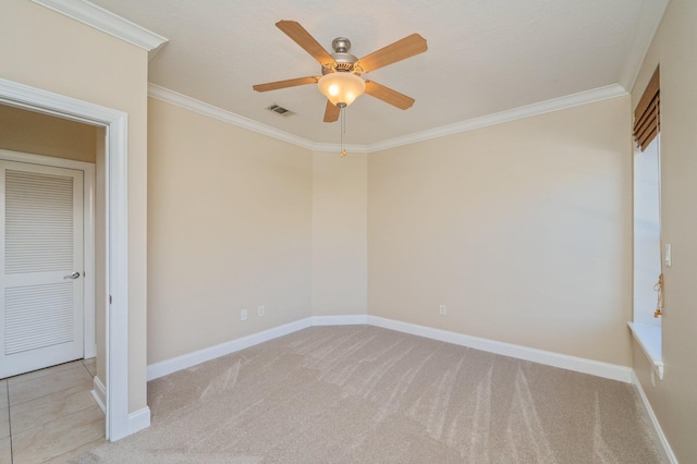 spare room with ceiling fan, ornamental molding, and light carpet