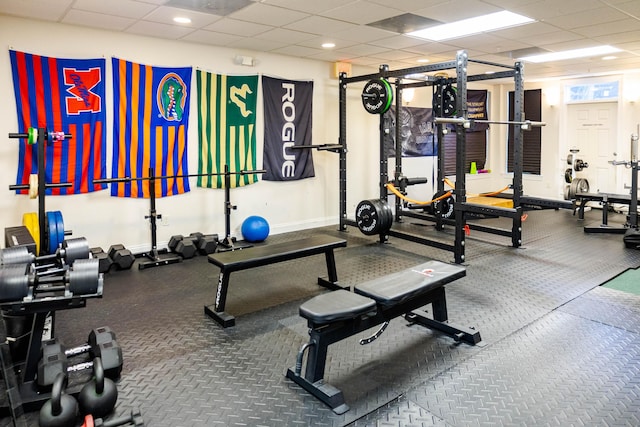 workout area featuring baseboards and a drop ceiling