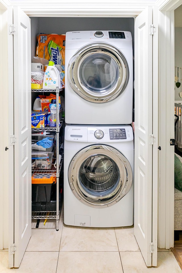 laundry room featuring laundry area, stacked washer / dryer, and light tile patterned flooring