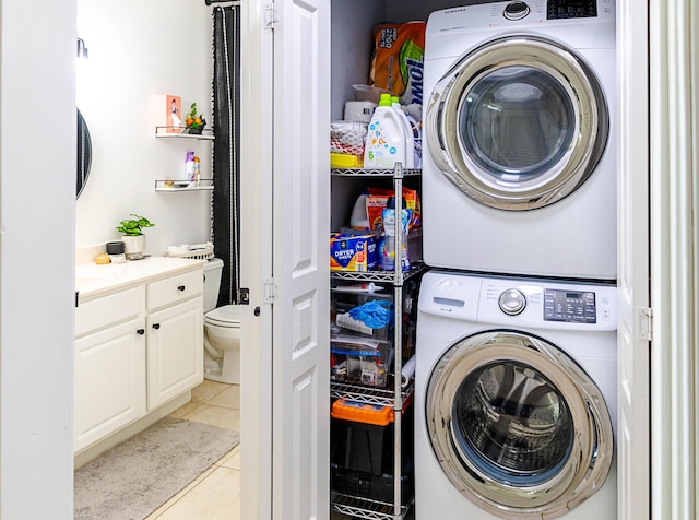 laundry area featuring stacked washer / drying machine, laundry area, and light tile patterned flooring