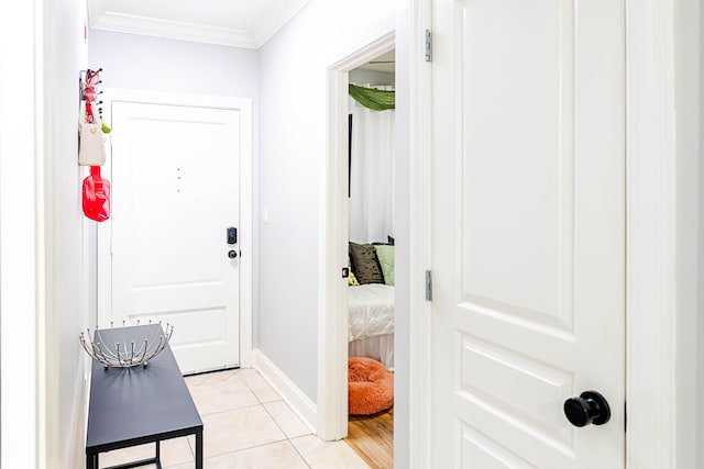 doorway featuring ornamental molding, light tile patterned flooring, and baseboards