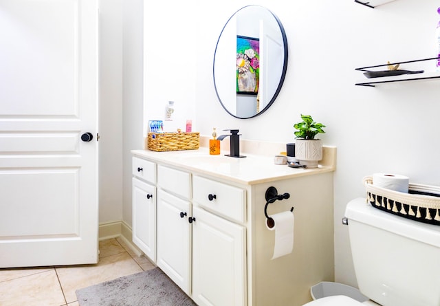 half bath with toilet, tile patterned floors, and vanity