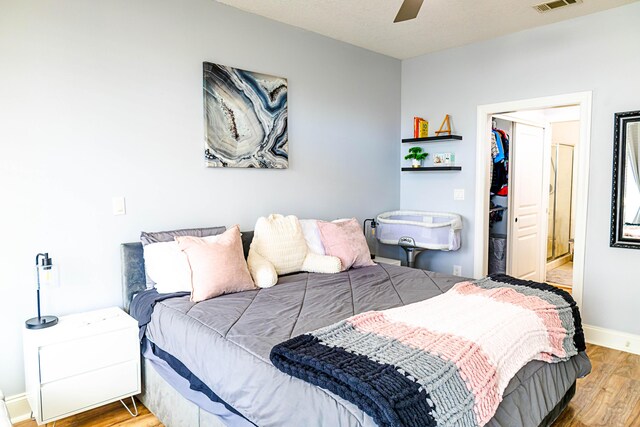 bedroom featuring wood finished floors, visible vents, baseboards, a spacious closet, and a closet