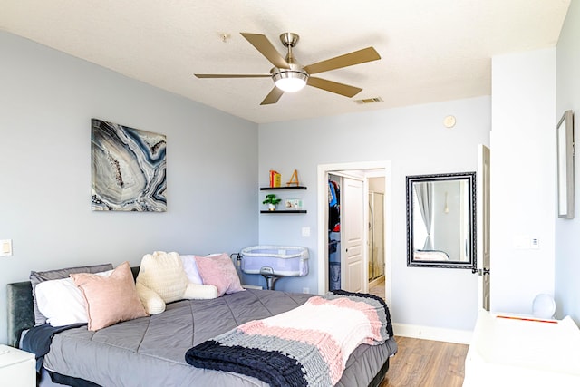 bedroom featuring visible vents, ceiling fan, wood finished floors, a spacious closet, and a closet