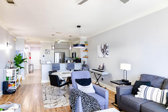 living room featuring ornamental molding, light wood-type flooring, visible vents, and baseboards