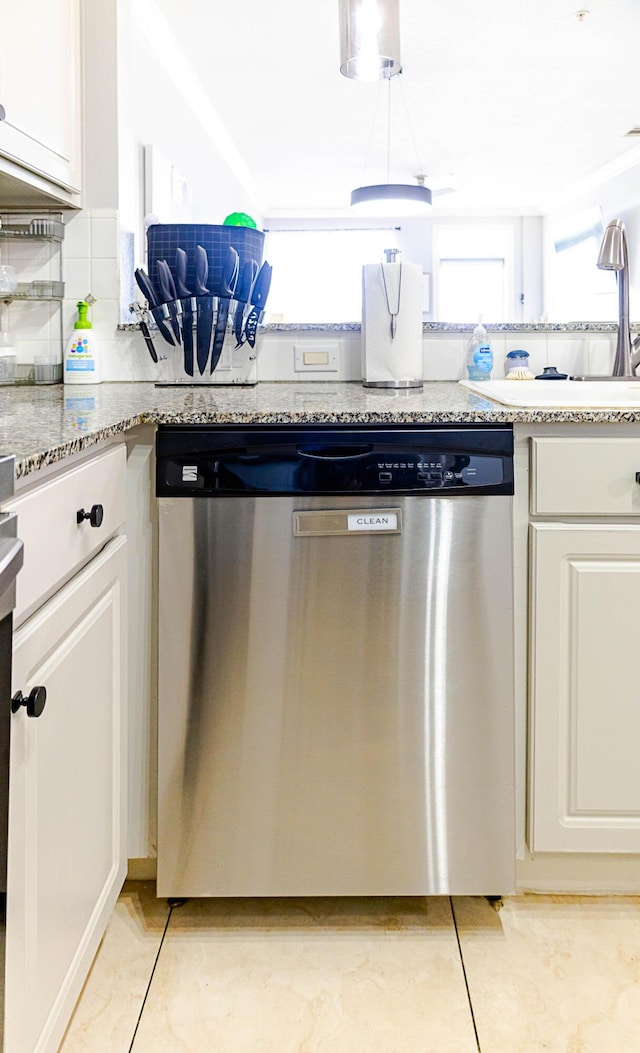 kitchen with tasteful backsplash, white cabinets, light stone counters, stainless steel dishwasher, and a sink