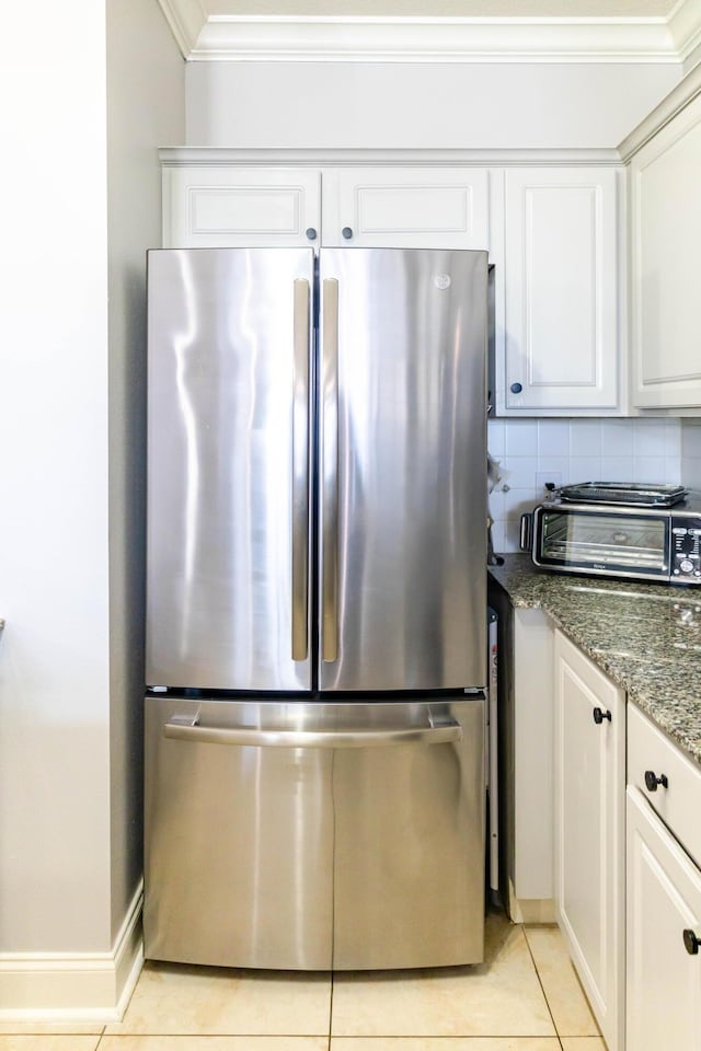 kitchen featuring a toaster, crown molding, light tile patterned floors, tasteful backsplash, and freestanding refrigerator