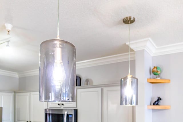 details featuring white cabinetry, stainless steel microwave, and crown molding