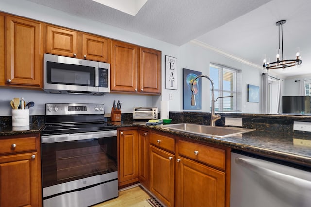 kitchen with stainless steel appliances, crown molding, sink, pendant lighting, and a chandelier