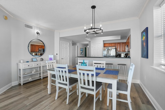 dining room with light wood-type flooring, an inviting chandelier, and crown molding