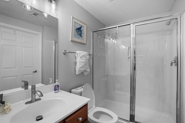 bathroom featuring toilet, an enclosed shower, a textured ceiling, and vanity