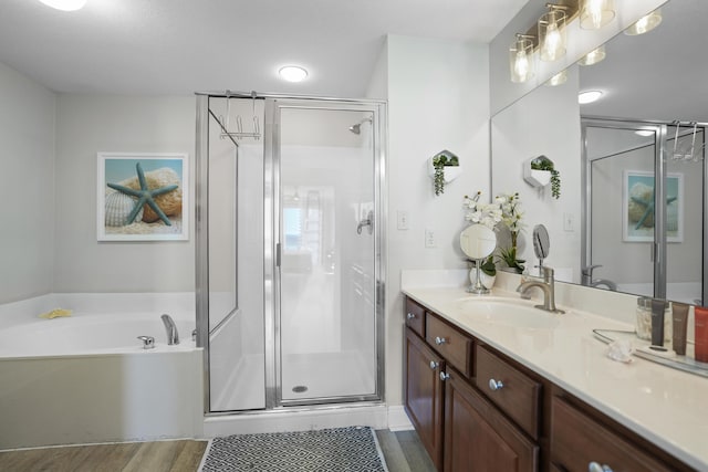 bathroom with hardwood / wood-style floors, vanity, and independent shower and bath