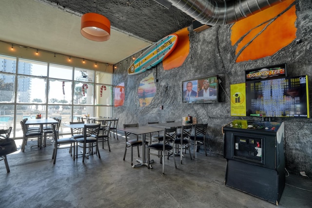 dining room featuring a towering ceiling and concrete floors