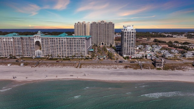 aerial view at dusk with a view of the beach and a water view