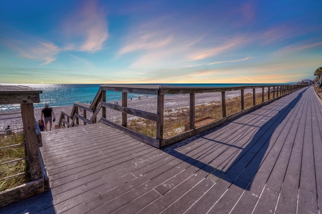 deck at dusk featuring a water view and a view of the beach