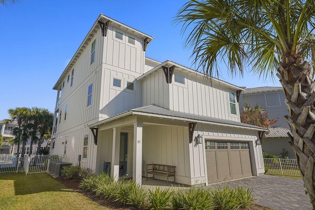 back of property with a porch, a garage, a lawn, and central air condition unit