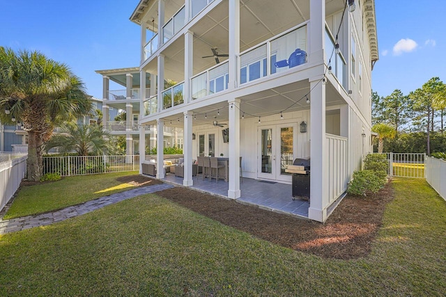 back of property with french doors, a balcony, ceiling fan, a patio area, and a lawn