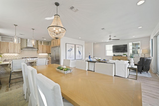 dining room featuring light hardwood / wood-style floors and ceiling fan with notable chandelier