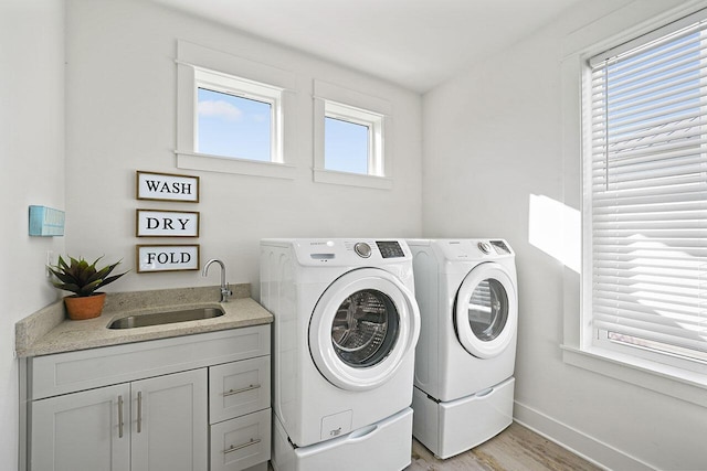 laundry room with washing machine and clothes dryer, sink, and light hardwood / wood-style flooring