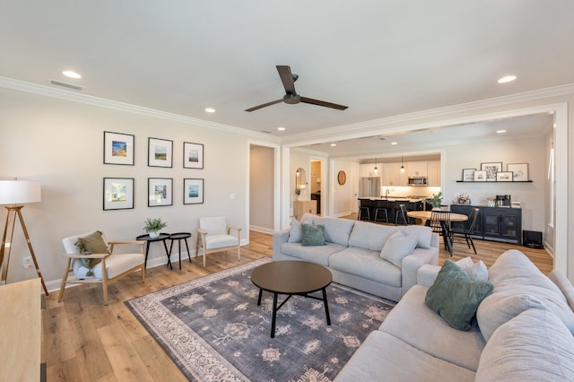 living room with light hardwood / wood-style flooring, ceiling fan, and ornamental molding