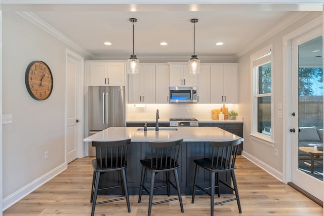 kitchen with stainless steel appliances, sink, light hardwood / wood-style flooring, white cabinetry, and an island with sink