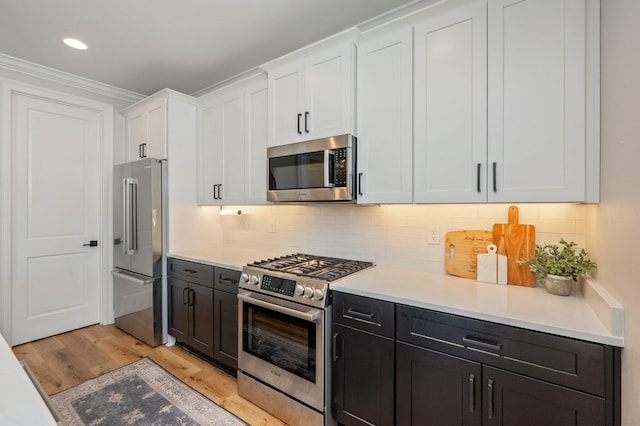 kitchen with white cabinetry, light hardwood / wood-style flooring, crown molding, decorative backsplash, and high end appliances