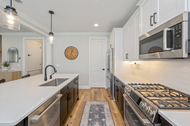 kitchen with backsplash, high end appliances, sink, decorative light fixtures, and white cabinets