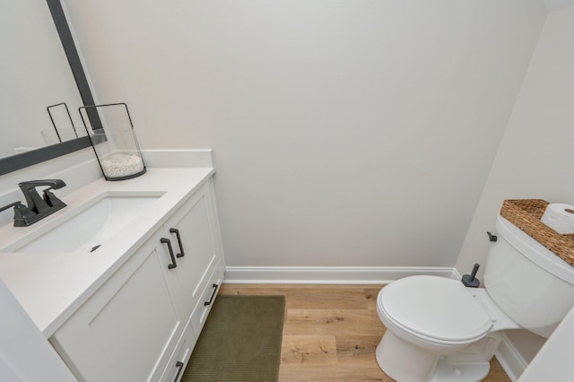 bathroom with toilet, vanity, and hardwood / wood-style flooring