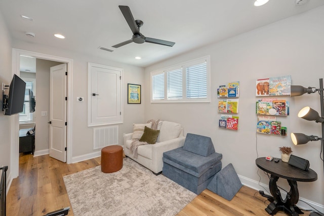 sitting room with light wood-type flooring, ceiling fan, and a healthy amount of sunlight