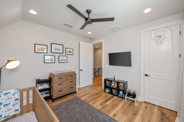 bedroom featuring lofted ceiling, ceiling fan, light hardwood / wood-style floors, and a crib