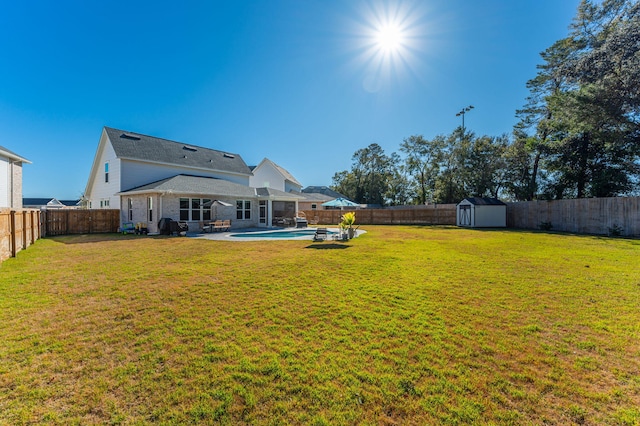 view of yard featuring a patio area, a fenced in pool, and a storage shed