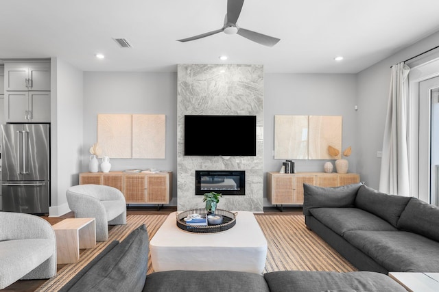 living room with a large fireplace, hardwood / wood-style floors, and ceiling fan