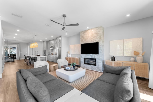 living room with hardwood / wood-style floors, a premium fireplace, and ceiling fan