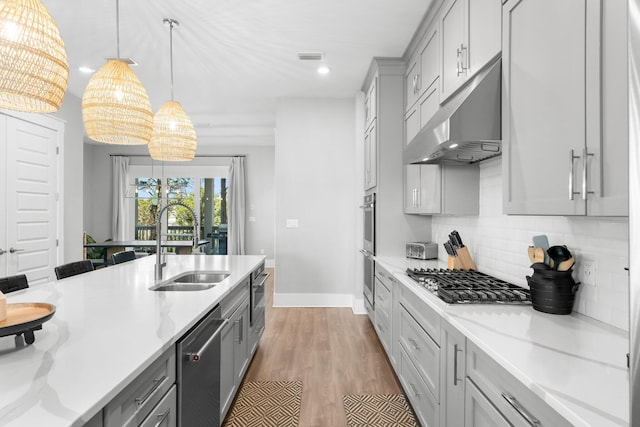 kitchen featuring appliances with stainless steel finishes, decorative light fixtures, tasteful backsplash, sink, and gray cabinetry