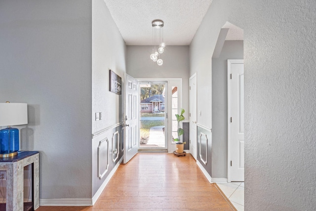 hallway with a textured ceiling and light wood-type flooring