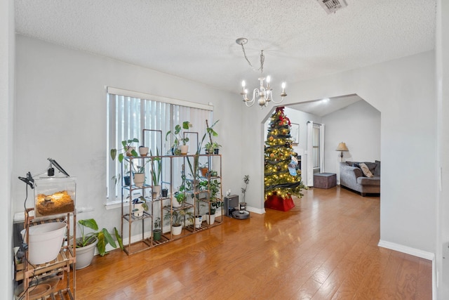 interior space featuring hardwood / wood-style flooring, a textured ceiling, and an inviting chandelier