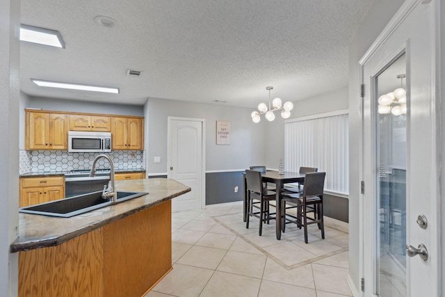 kitchen featuring stainless steel electric range oven, an inviting chandelier, backsplash, pendant lighting, and light tile patterned floors