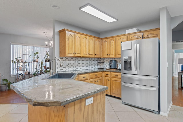 kitchen with sink, stainless steel fridge with ice dispenser, light tile patterned flooring, kitchen peninsula, and a chandelier