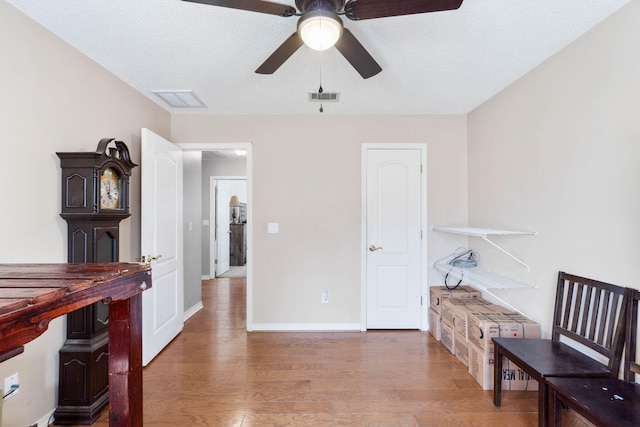 interior space with a textured ceiling, hardwood / wood-style flooring, and ceiling fan