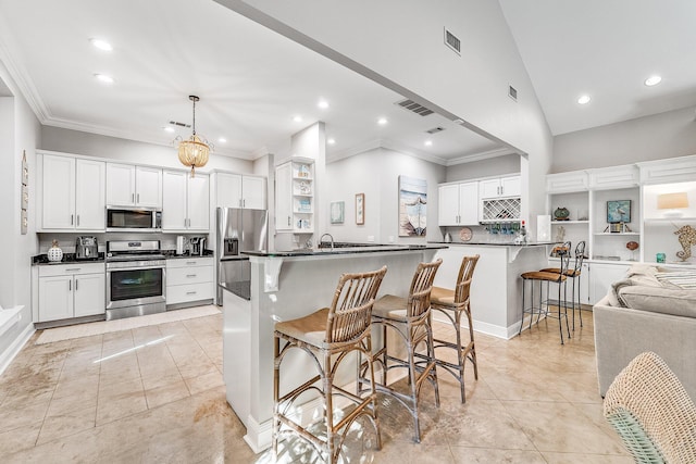 kitchen featuring white cabinets, a kitchen breakfast bar, vaulted ceiling, appliances with stainless steel finishes, and decorative light fixtures